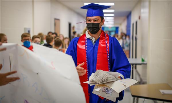 A senior walks to accept a sign from an elementary student